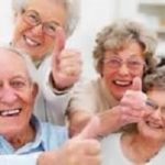 Four elderly people smiling and showing "like" sign